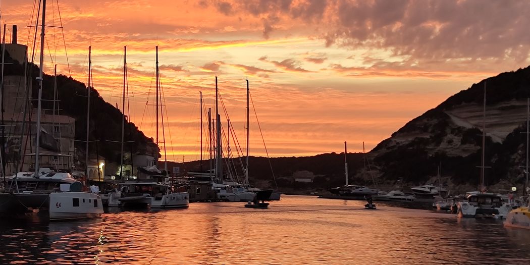 Sonnenuntergang über einem Hafen mit Segelbooten, der Himmel orange